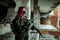 Airsoft red-head woman in uniform and put down machine gun. Soldier standing on balkony. Horizontal photo side view