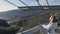 Airy pedestrian bridge construction over abyss, skybridge observation deck. Woman enjoing sunlight and scenery view