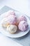 Airy white and pink marshmallows on a white plate on a light background