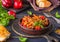 Ajapsandali, cold vegetable stew or appetizer of eggplant, pepper, tomato and carrots in a clay bowl on a brown wooden background