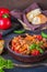 Ajapsandali, cold vegetable stew or appetizer of eggplant, pepper, tomato and carrots in a clay bowl on a brown wooden background