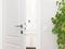 Ajar white door to the bathroom. Series switch on a light gray w