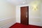 Ajar wooden door, red carpet on floor