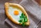 Ajarian khachapuri with egg and parsley on sackcloth, Georgian cuisine