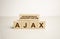 ajax is made up of wooden cubes that stand on a burgundy notebook near the pen. Business concept