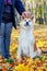 Akita dog with a mistress in the autumn park among the yellow fallen leaves