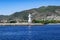 Alanya lighthouse with the Turkish flag on the roof against the background of a mountain panorama of the Mediterranean coast.