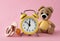 Alarm clock, baby dummy and toy bear on pink background. Time to give birth