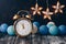 Alarm Clock, blue balls and stars garland. Wooden old table. Selective focus. New Year or Christmas background