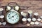 Alarm clock and coin pile on wooden table with blur green garden background, bright morning color tone, finance and business