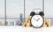 An alarm clock is on the foreground and golden coins which are on the background. Modern New York panoramic office on background.