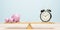 Alarm clock and piggy bank balancing on seesaw. Time is money concept.3d illustration