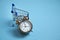 Alarm clock, shopping cart on the blue background