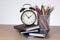 Alarm clock standing on books with colored pencils