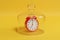 Alarm clock under glass bell isolated on yellow background.