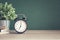 Alarm clock on wooden table on blackboard background in classroom,back to school concept