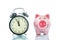 Alarmclock with piggybank on white background