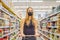 Alarmed female wears medical mask against coronavirus while grocery shopping in supermarket or store- health, safety and