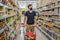 Alarmed man wears medical mask against coronavirus while grocery shopping in supermarket or store- health, safety and