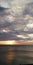 Alarming background. Autumn sunset seascape. Clouds, sea and setting sun