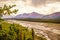 Alaskan mountians in Denali National Park viewed over braided river - runoff from a glacier framed with pine trees under smokey