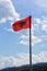 Albania flag against blue sky with white clouds.