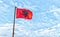 Albania flag against blue sky with white clouds.