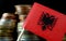 Albanian flag waving with stack of money coins