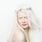 Albino female with wreath and white long hair. Photo face on a light background. Blonde girl