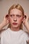 Albino feminine man tucks his hair behind ears while posing in studio