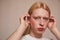 Albino feminine man tucks his hair behind ears while posing in studio