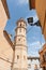 Alcalali church spire rising through narrow typically historic Mediterranean village street, Spain