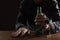 Alcohol addiction. Man chained with bottle of beer at wooden table, closeup