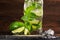 Alcohol and fresh mojito drink with rum, fresh lime, mint, crushed ice and sugar on a dark wooden background. Summer beverages.