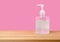 Alcohol gel bottles, wash hands on wooden tables and have a pink background