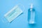 Alcohol hand sanitizer gel bottle with surgical face mask on blue background protection against COVID-19 coronavirus. Healthcare