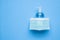 Alcohol hand sanitizer gel bottle with surgical face mask on blue background protection against COVID-19 coronavirus. Healthcare