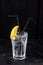 Alcohol transparent cocktail with ice and lemon on black background