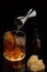Alcoholic cocktail Old fashioned cocktail with orange slice, spilling bourbon from the double jigger, Glass Dropper Bottle with
