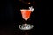 Alcoholic cocktail of pink color stands on a special plate on a black background