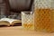 Alcoholic drink in crystal decanter. In a glass poured whiskey on a wooden table in the background a chair for seating. Open book