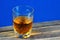 Alcoholic drink in a glass on a wooden table top, blue background. Strong aromatic alcoholic drink, from different types of grain