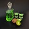 Alcoholic tincture on kiwi, homemade liqueur in a glass bottle and two glasses on a black background, close-up of ripe fruits