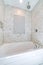 Alcove bathtub with marble subway tile surround and shower head