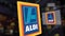 Aldi logo on the glass against blurred business center. Editorial 3D rendering