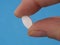 Alendronate sodium tablet between fingers, a nonhormonal medication for treating postmenopausal osteoporosis in women.