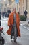 Alex Badia with orange coat and grey jacket and trousers before Giorgio Armani fashion show,