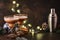 Alexander cocktail in cocktail glass on wooden table with shaker, nutmeg and small grater with Christmas decor on dark background