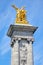 Alexandre III bridge golden statue with winged horse and column, blue sky in Paris, France