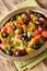 Algerian salad Chlada felfel with green pepper tomato, anchovies and mix of olives close-up in a bowl. vertical